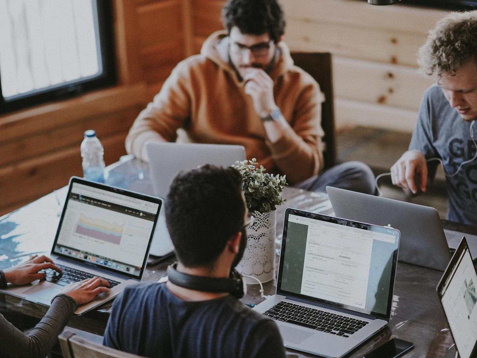 A small team collaborating around a table with laptops